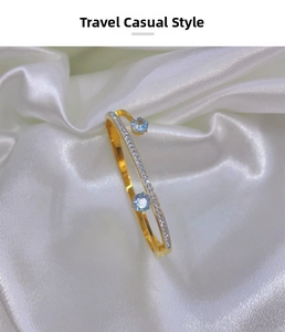 Detail of a golden bangle with double parallel bands and blue gemstone accents
