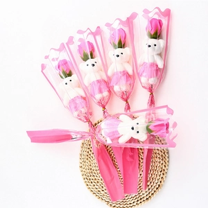 Flat lay of pink soap rose bouquets with cute white bears on a straw mat background