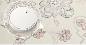 Detail of floral rug surface being cleaned easily by a white robot vacuum cleaner