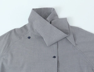 Détail d'une chemise en popeline à carreaux bleu-gris avec col croisé et bouton foncé