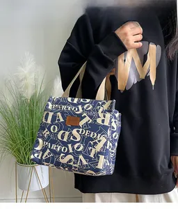 Détail du sac à lunch en toile marine avec imprimés lettres et écusson en cuir