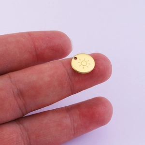 Polished 18K gold plated stainless steel sun pendant charm shown for size scale