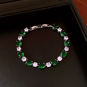 Macro shot of silver bracelet with green oval and white round stones in a black gift box