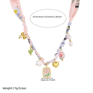 Detail of floral ribbon chain necklace with pearl and heart charms on white background