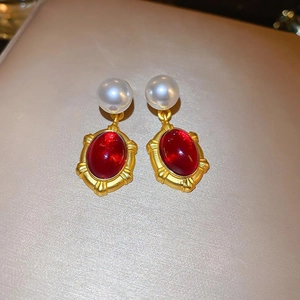 Macro view of vintage earrings with pearl and oval red gemstone in gold frame
