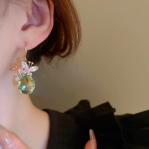 Close-up of zircon butterfly drop earring with light green crystal on female model