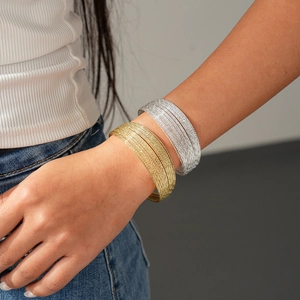 Detail of layered gold and silver wide bangles showing fine multi-strand metal wire texture
