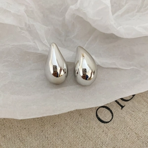 Macro detail of polished silver teardrop earrings with a sleek metallic mirror finish