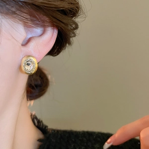 Detailed close-up showing a vintage oval stud earring with diamonds worn on the ear lobe