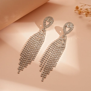 Detail of silver long tassel earrings with sparkling rhinestones on a soft background