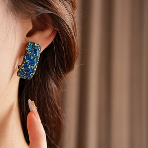Détail d'une boucle d'oreille bohème rectangulaire avec cristal bleu sur l'oreille