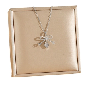 Silver bow and heart pendant necklace with zircon crystals on a jewelry display box