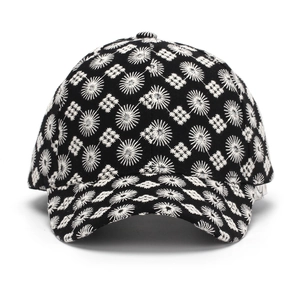 Detalle de gorra negra con bordado blanco de patrones solares y diseño geométrico