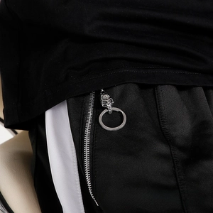 Detail of gothic silver skull charm attached to a black sport trousers zipper