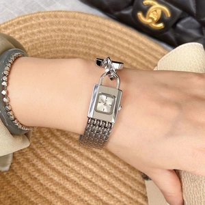 Close-up of a silver rectangular padlock watch with metal chain strap on a wrist