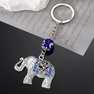 Vintage elephant keychain with blue evil eye bead and rhinestones on dark background