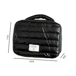 Detail of black quilted makeup bag showing dimensions 23x17x9cm with top handle