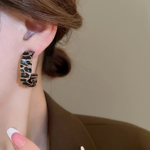 Close-up of leopard print C-shape resin hoop earrings on a model for a vintage look