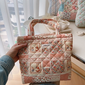 Close-up of quilted tote bag with floral patchwork, rabbit pattern and a simple wish label