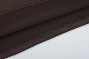 Gros plan sur la couture surjetée de qualité de l'ourlet en maille marron foncé