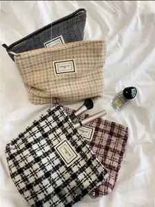 Macro detail of tweed checkered cosmetic bags with metal zipper and logo patch