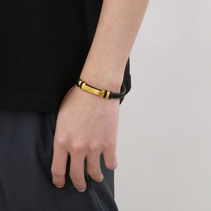 Close-up of black braided leather bracelet with gold metal bar on male wrist
