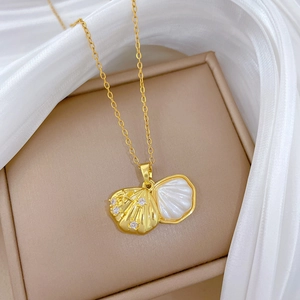 Dettaglio macro di una collana con ciondolo a conchiglia dorata e diamanti su scatola