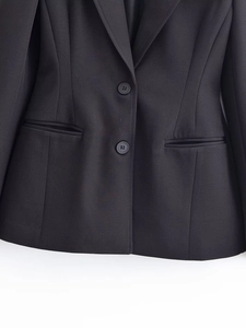 Détail d'un blazer noir avec revers à encoche, deux boutons et poches à rabat