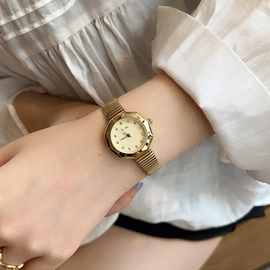 Elegant gold octagonal ladies watch with elastic metal strap worn on wrist