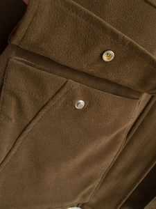 Detailansicht der dunkelbraunen Wildleder-Bomberjacke mit Metalldruckknöpfen und Tasche