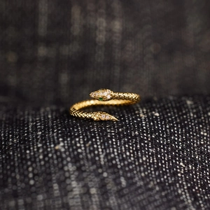 Close-up of golden snake ring with cubic zirconia paving and green gemstone eyes