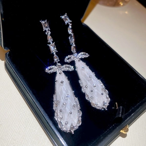 Close-up of bow knot drop earrings with pear-shaped quilted pendants on black velvet