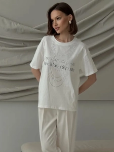 Close-up of white cotton T-shirt featuring precious deposits print and pearl necklace detail