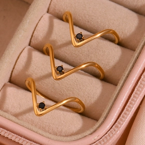 Detailed view of three 18K gold V-shaped rings with black stones in a pink velvet box