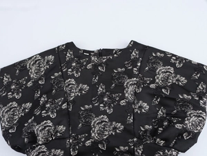 Close-up of black jacquard dress with silver rose pattern and puffy flutter sleeves