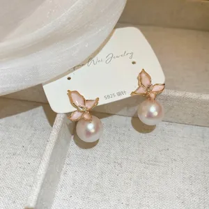 Détail de boucles d'oreilles papillon en émail rose avec perles et tiges en argent S925