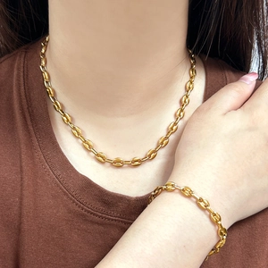 Close-up of gold coffee bean chain necklace and bracelet set worn by a model