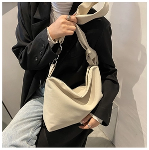 Close-up of beige canvas crossbody bag featuring a unique wide knotted shoulder strap detail