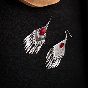 Macro detail of Bohemian silver earrings with red stone and hanging metal tassels