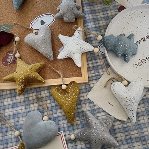 Close-up of plush star and heart ornaments with metallic texture and wooden beads