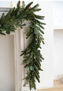 Lush green PE Christmas garland with pine needles and eucalyptus leaves on a fireplace