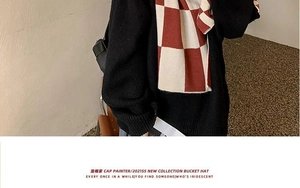 Detail shot of red and white checkerboard knit scarf paired with a black sweater