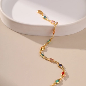 Exotic 18K gold plated bracelet with multi-color acrylic stones on a white ceramic tray