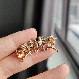 Detail view of the back of a colorful bird brooch showing the golden pin structure