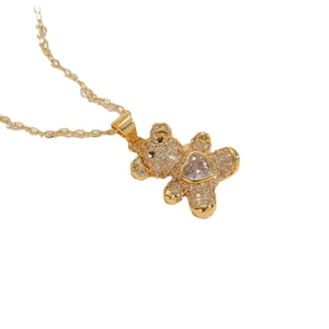 Golden teddy bear pendant necklace with heart-shaped zircon on white background