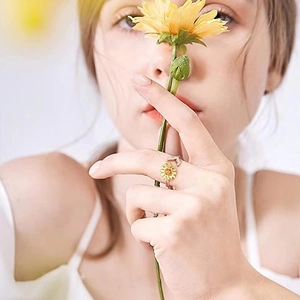 Detailed view of an adjustable gold sunflower ring with sparkling cubic zirconia on finger