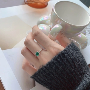 Detail of S925 silver ring with emerald zircon stone and diamond halo on model's finger