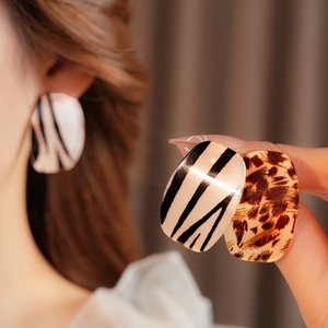 Detailed view of large square stud earrings featuring zebra and leopard print patterns