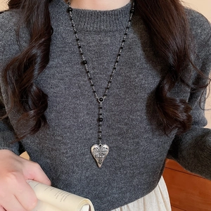 Détail d'un collier médaillon en forme de cœur vintage avec gravures et perles noires
