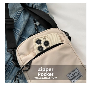 Detail of beige nylon crossbody bag featuring front zipper pocket and Hello Weekend label